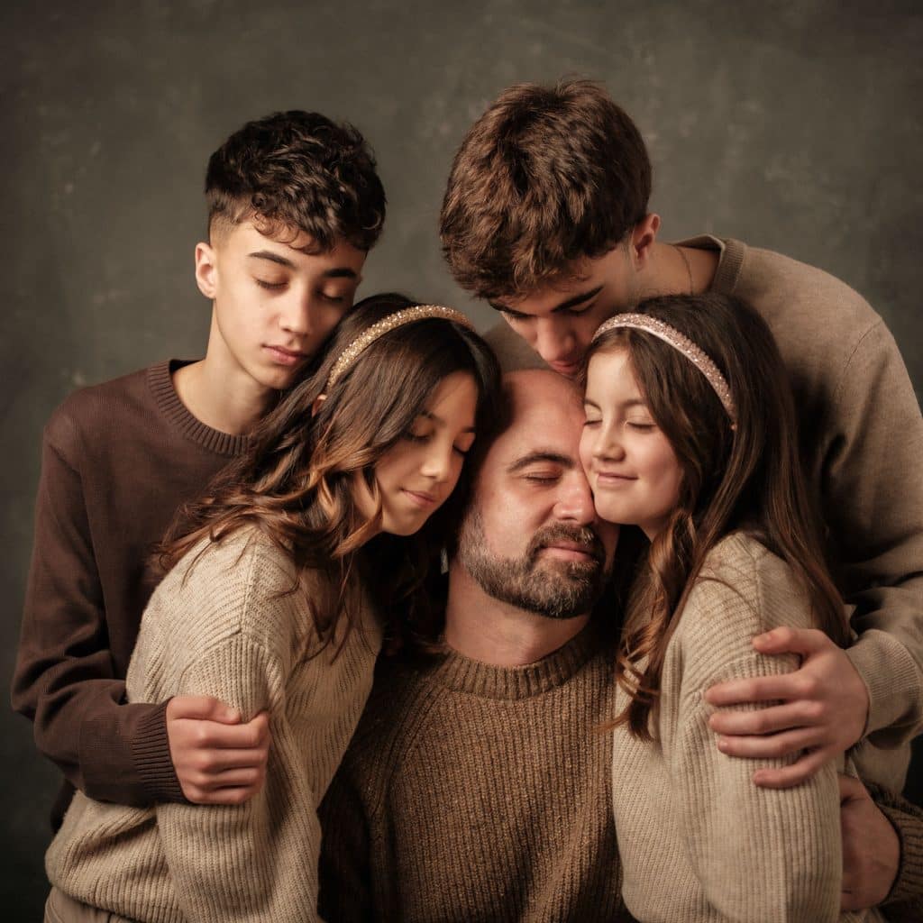 Papá abrazado por sus 4 hijos en sesión fotográfica del día del padre.