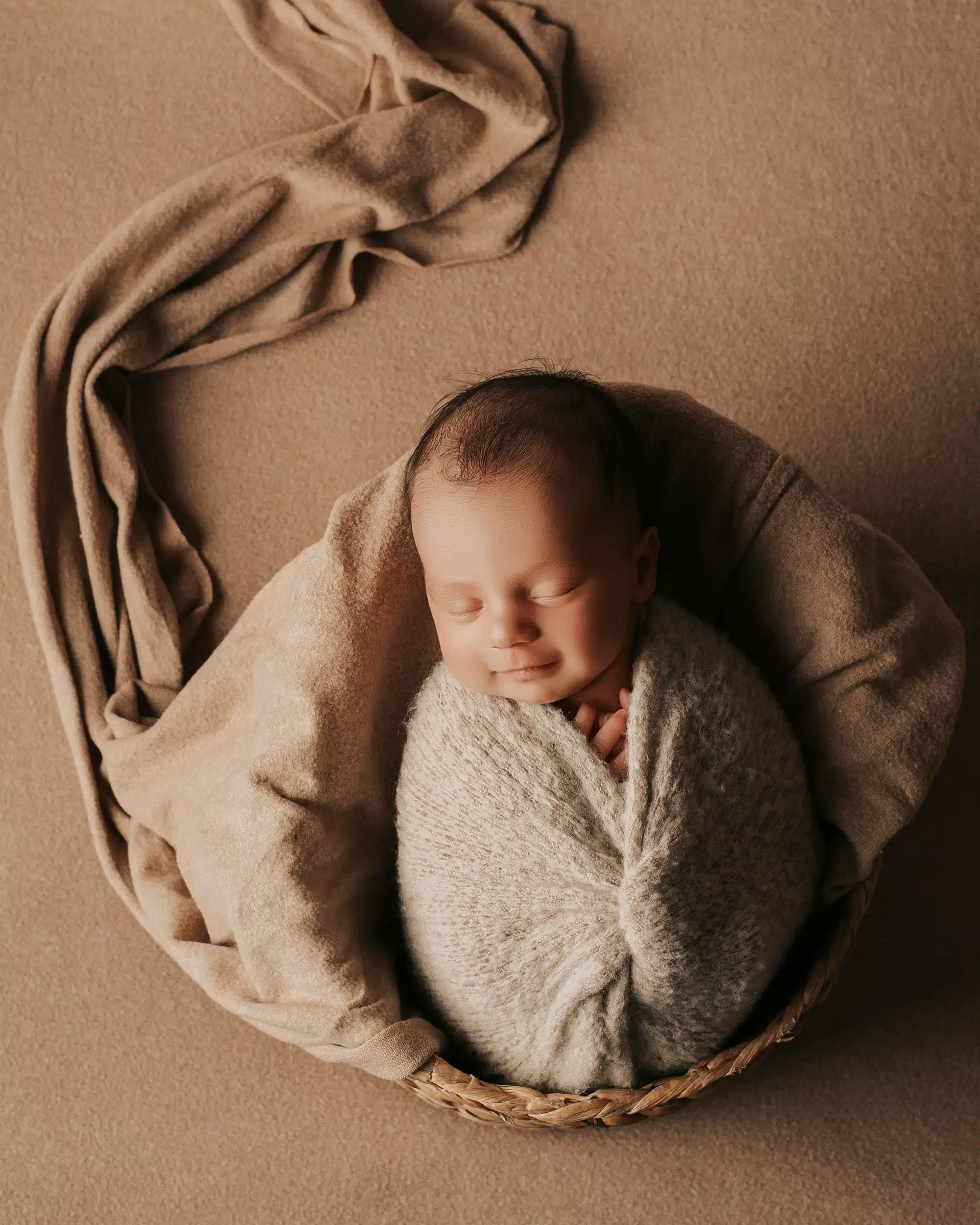 Bebé recién nacido en una canasta con iluminación suave en estudio fotografiado por Estudio M enArteixo A Coruña 02